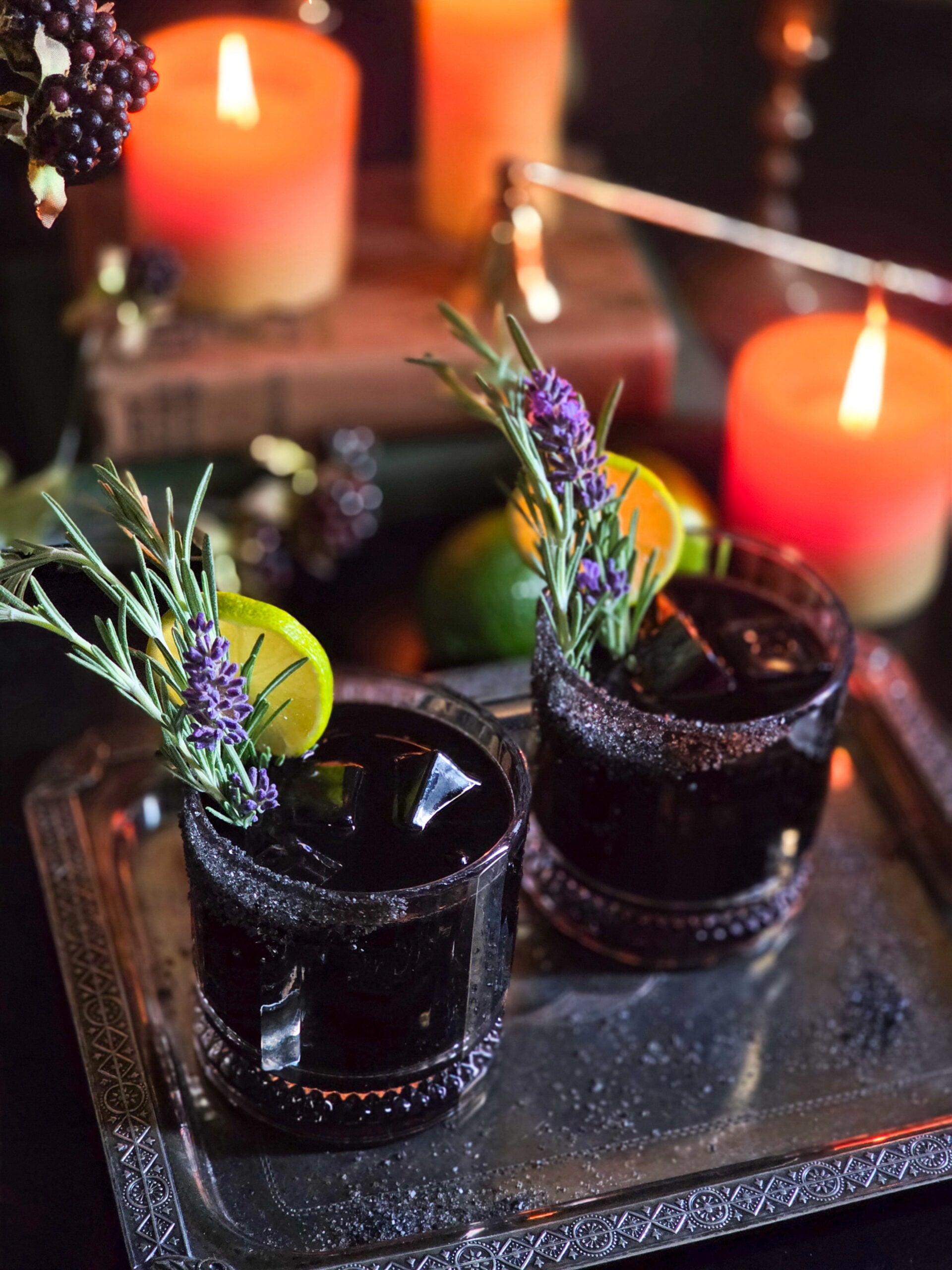 black magic margarita with candles lit and rosemary line lavender garnish