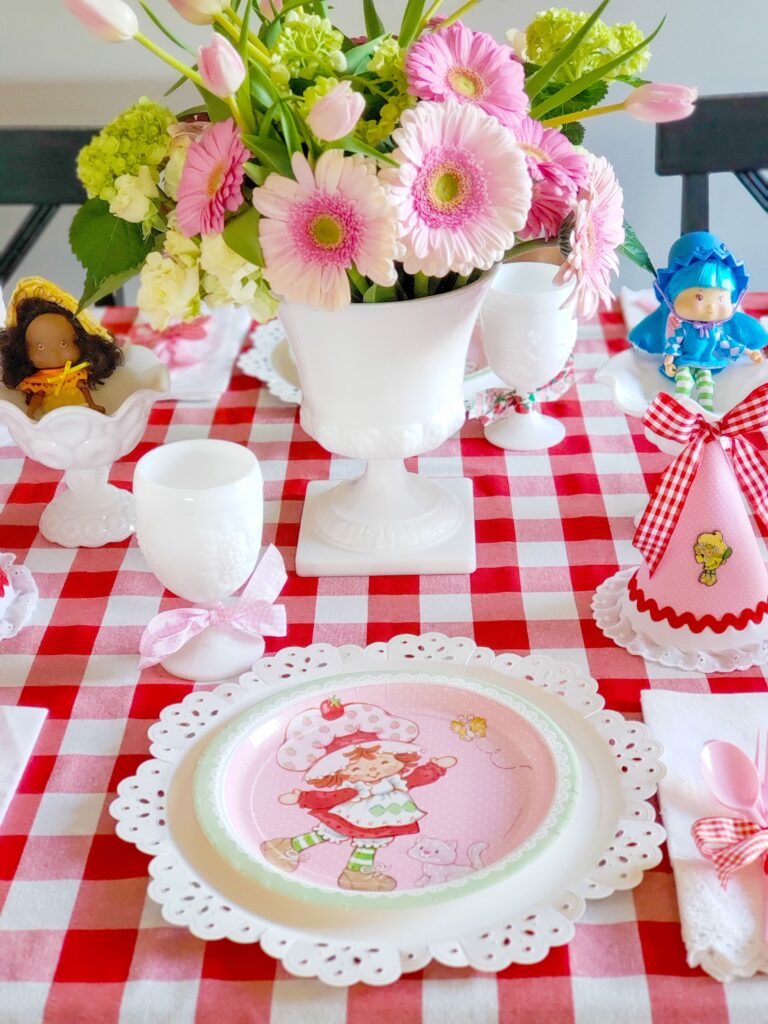 strawberry shortcake tablescape with paper plates, flowers and dolls