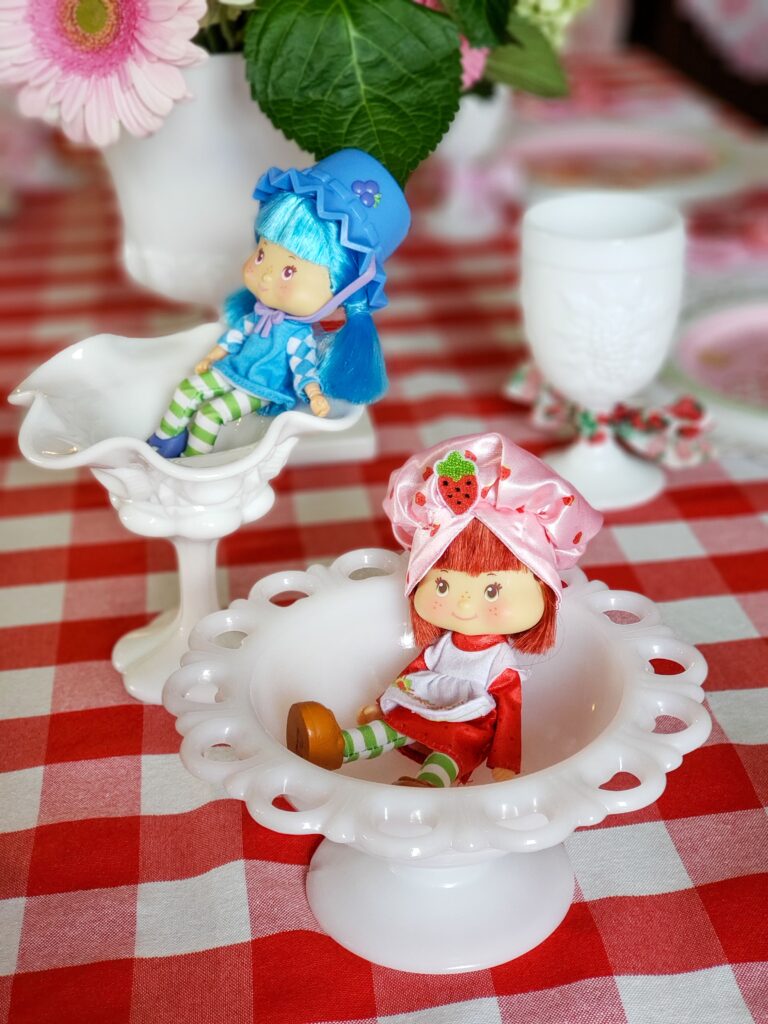 strawberry shortcake tablescape with dolls a gingham tablecloth