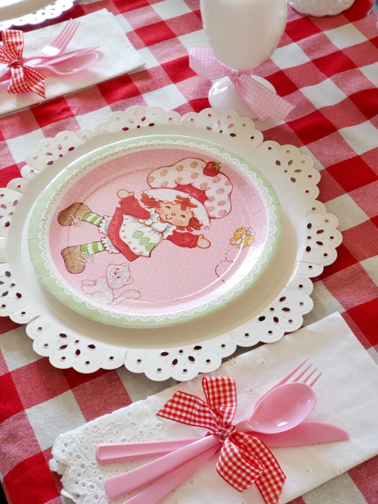 strawberry shortcake tablescape with paper plates and a gingham tablecloth