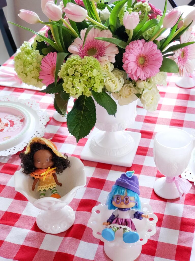 strawberry shortcake tablescape with dolls a gingham tablecloth