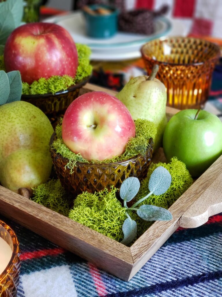 vintage thanksgiving tablescape with plush goose, colored glassware, plaid blankets, apples and pears.