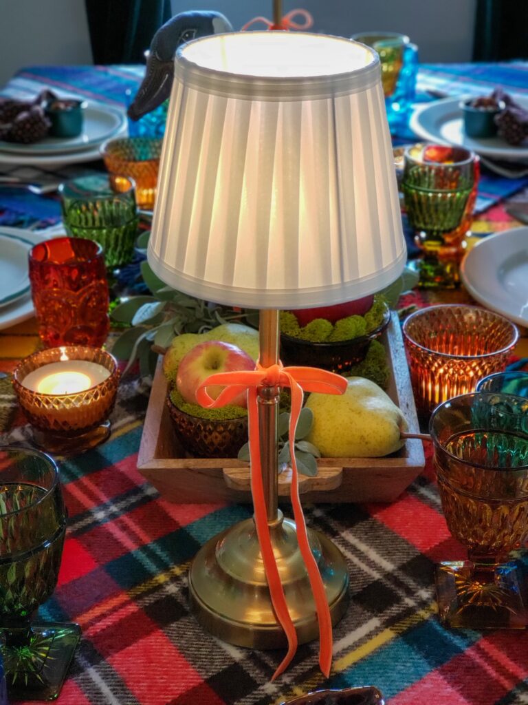 vintage thanksgiving tablescape with plush goose, colored glassware, plaid blankets, apples and pears.
