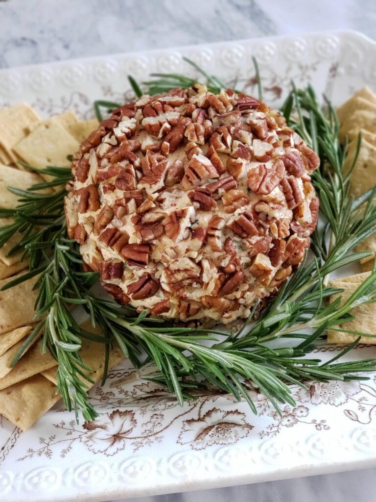 cheese ball with rosemary garnish and crackers