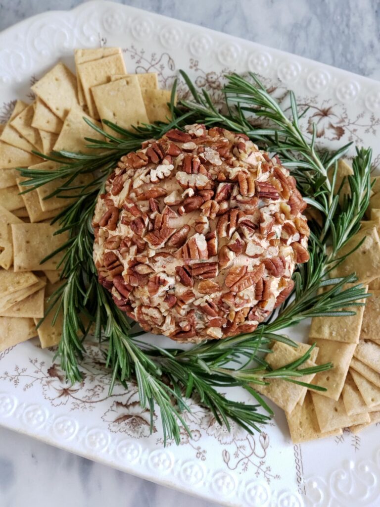 cheese ball with rosemary garnish and crackers