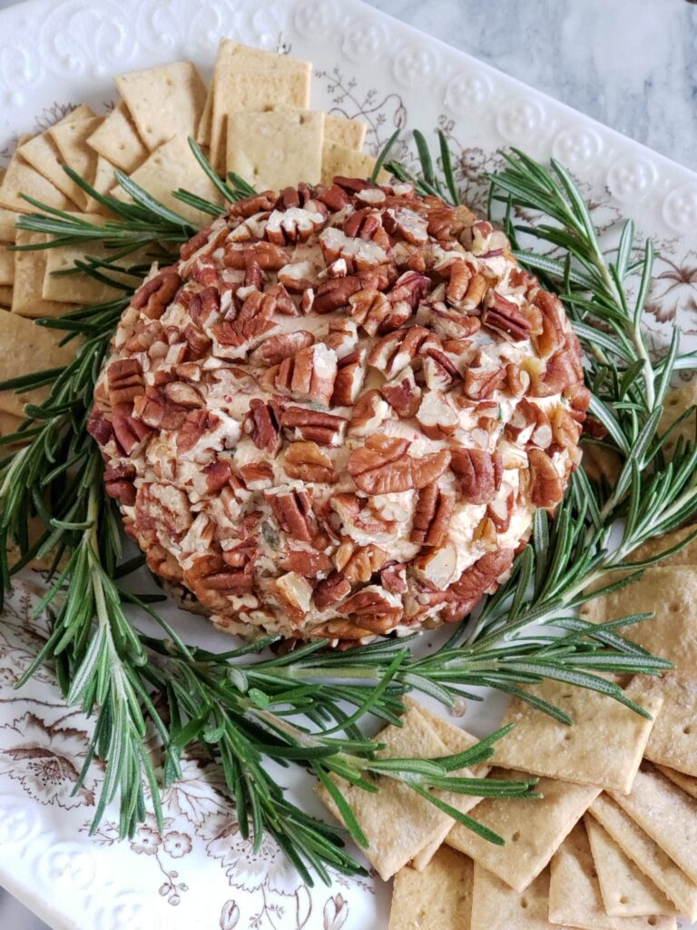 cheese ball with rosemary garnish and crackers