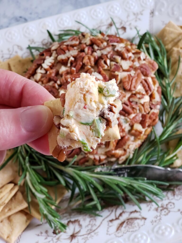 cheese ball with rosemary garnish and crackers