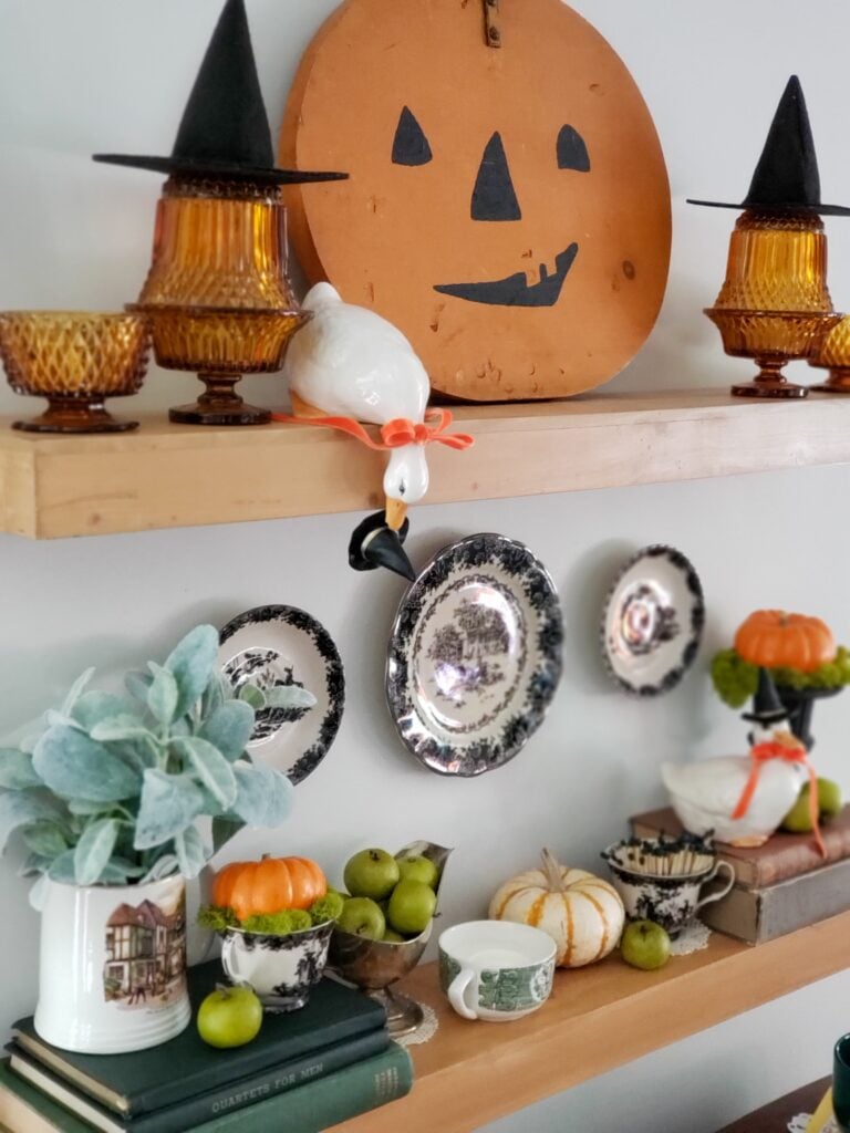 cozy cottage halloween decor with books, ducks in witch hats, pumpkins and teacups