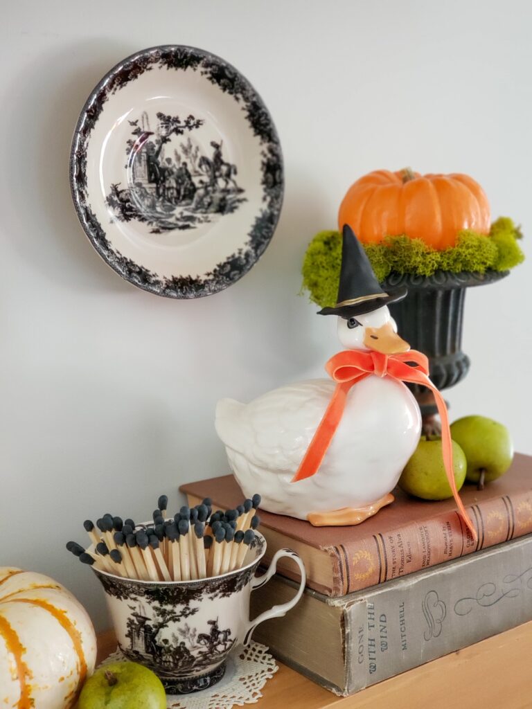 cozy cottage halloween decor with books, ducks in witch hats, pumpkins and teacups