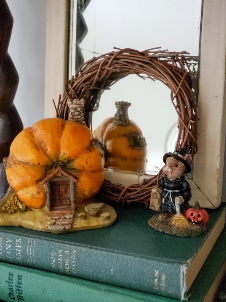 cozy cottage halloween decor with a cottage figurines sitting on books