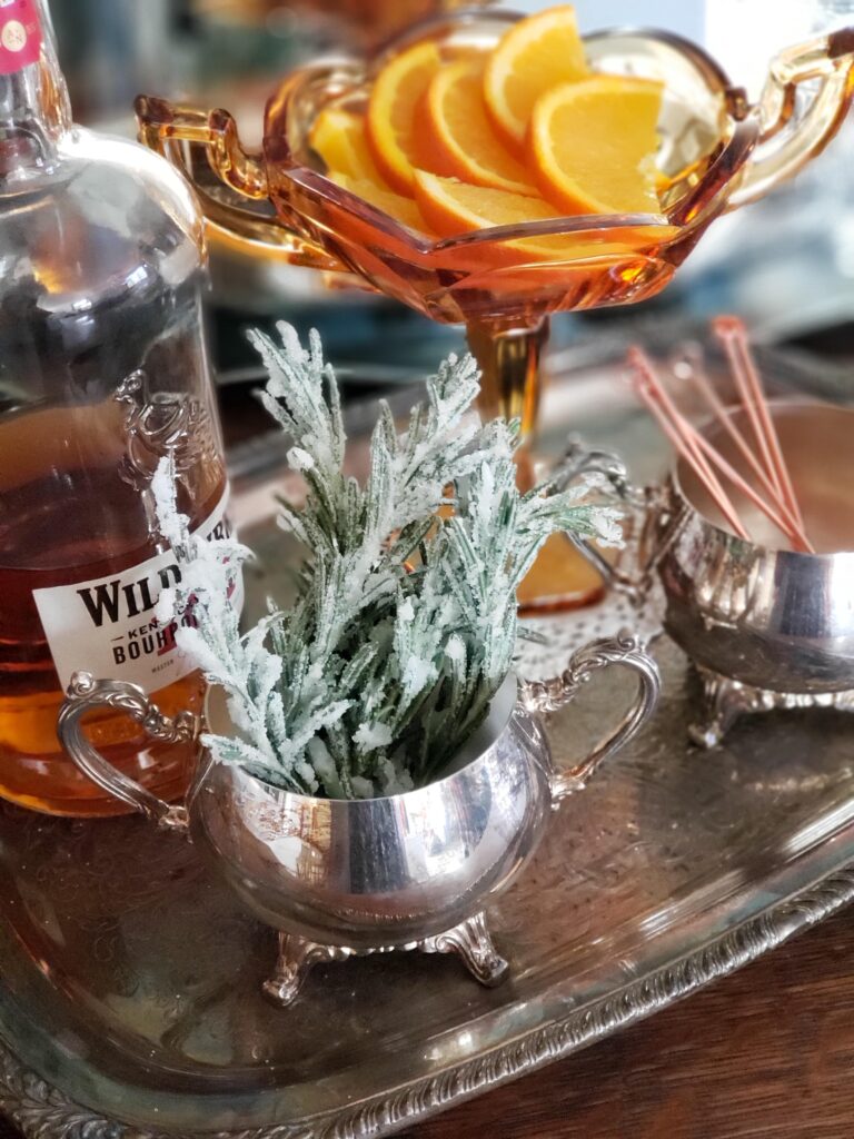 sugared rosemary in a silver dish with bourbon and cocktail accessories
