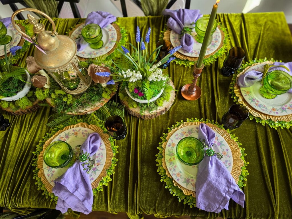 enchanted forest fairy party tablescape with velvet tablecloth, purple napkins and green glassware
