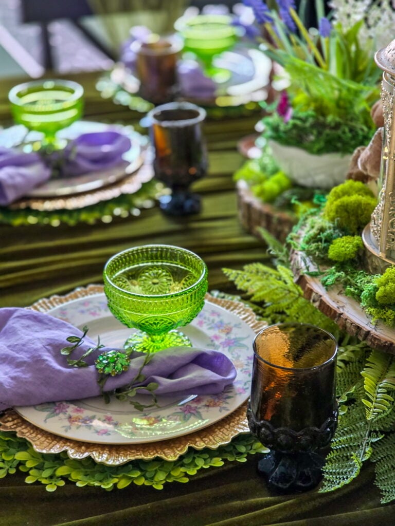 enchanted fairy party tablescape with brown and green glassware and purple napkin