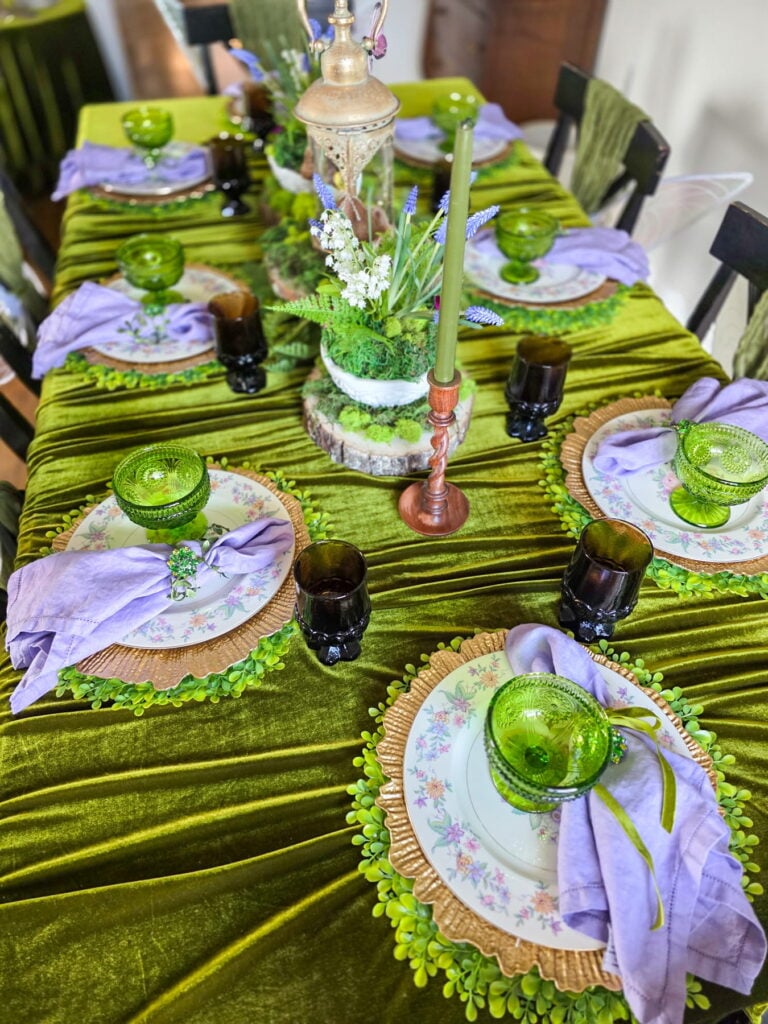 enchanted forest fairy party tablescape with velvet tablecloth, purple napkins and green glassware
