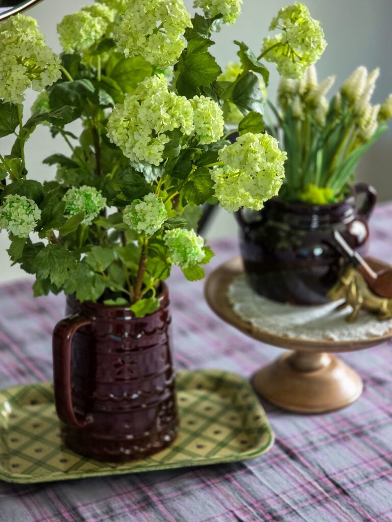 brown vintage pitcher on green tray with faux hydrangeas