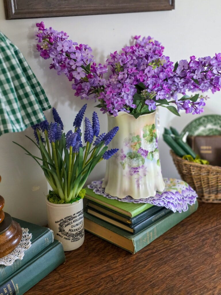 antique pitcher with lilacs in it on stack of books