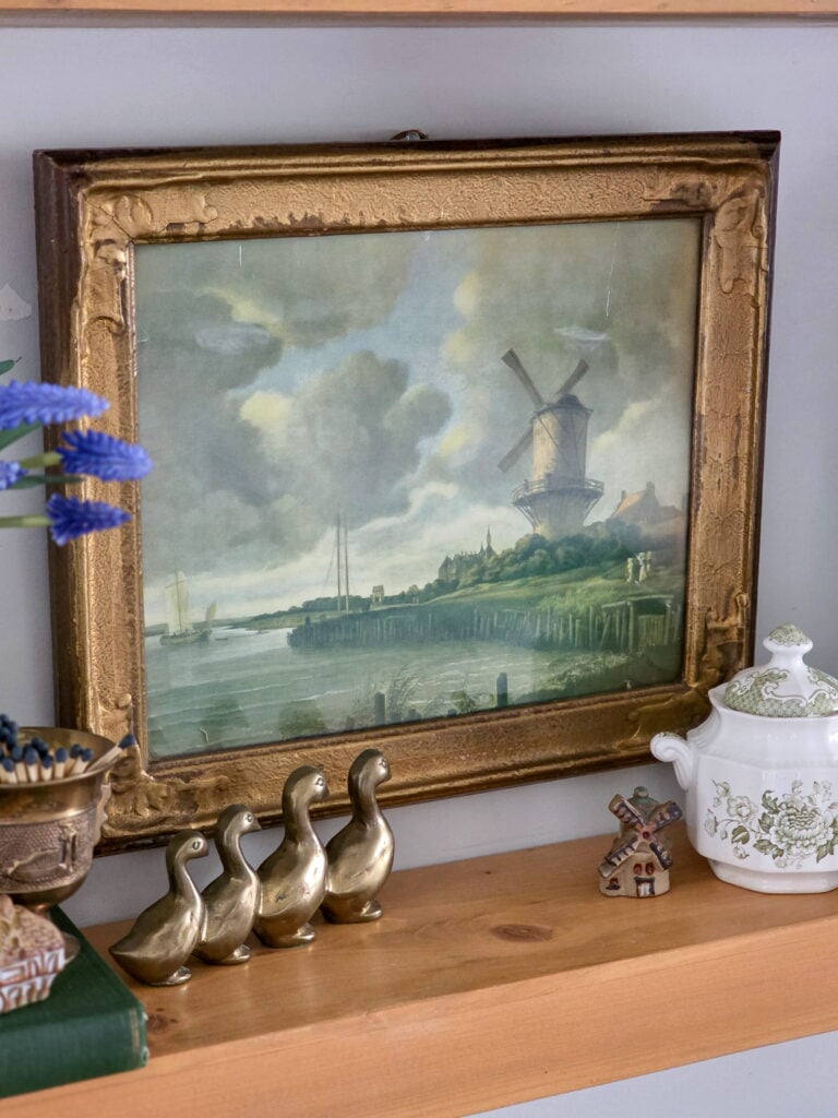 vintage art print above shelf and brass ducks in front