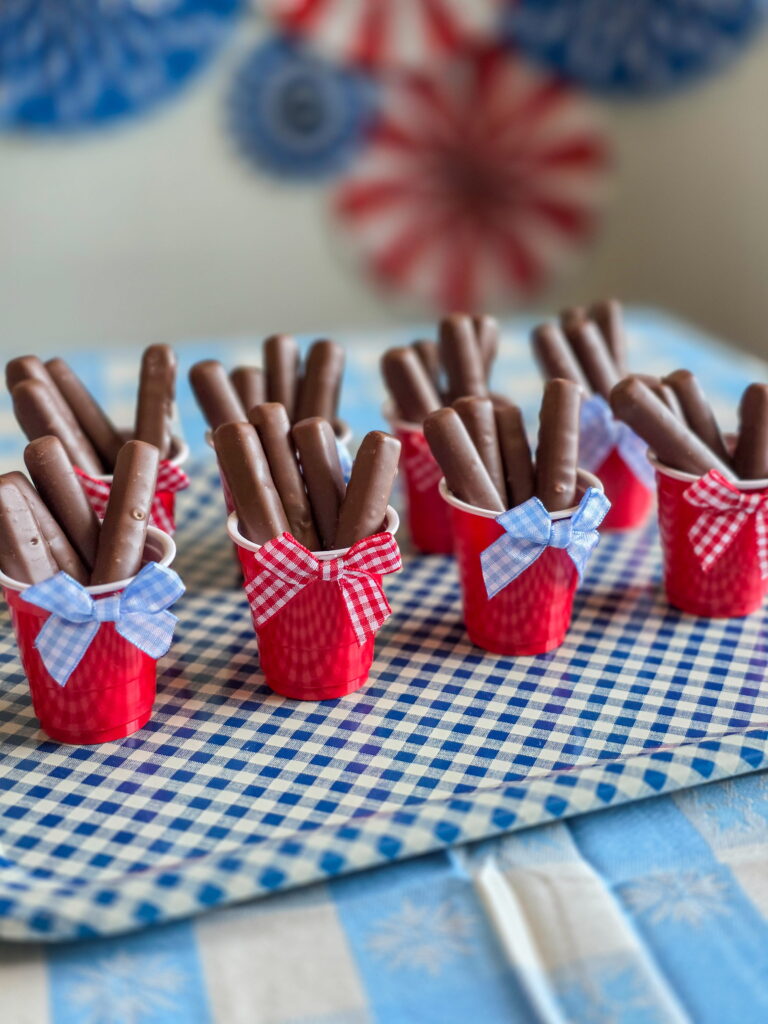DIY vintage Americana party favor with chocolate raspberry sticks in mini red cups and gingham bow
