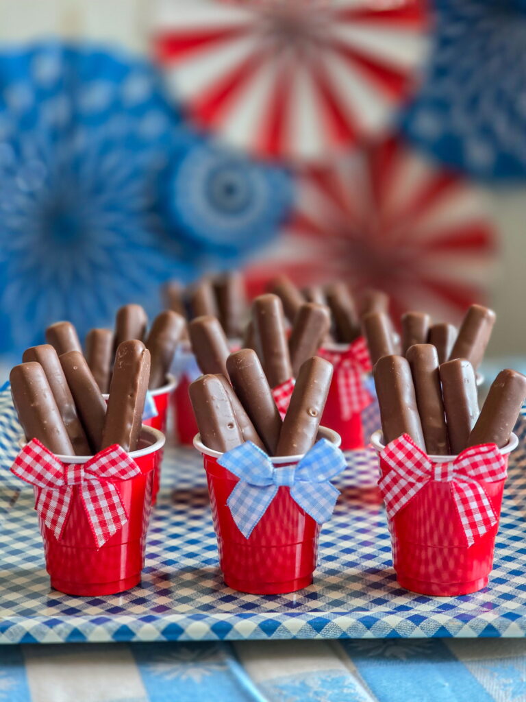 DIY vintage Americana party favor with chocolate raspberry sticks in mini red cups and gingham bow