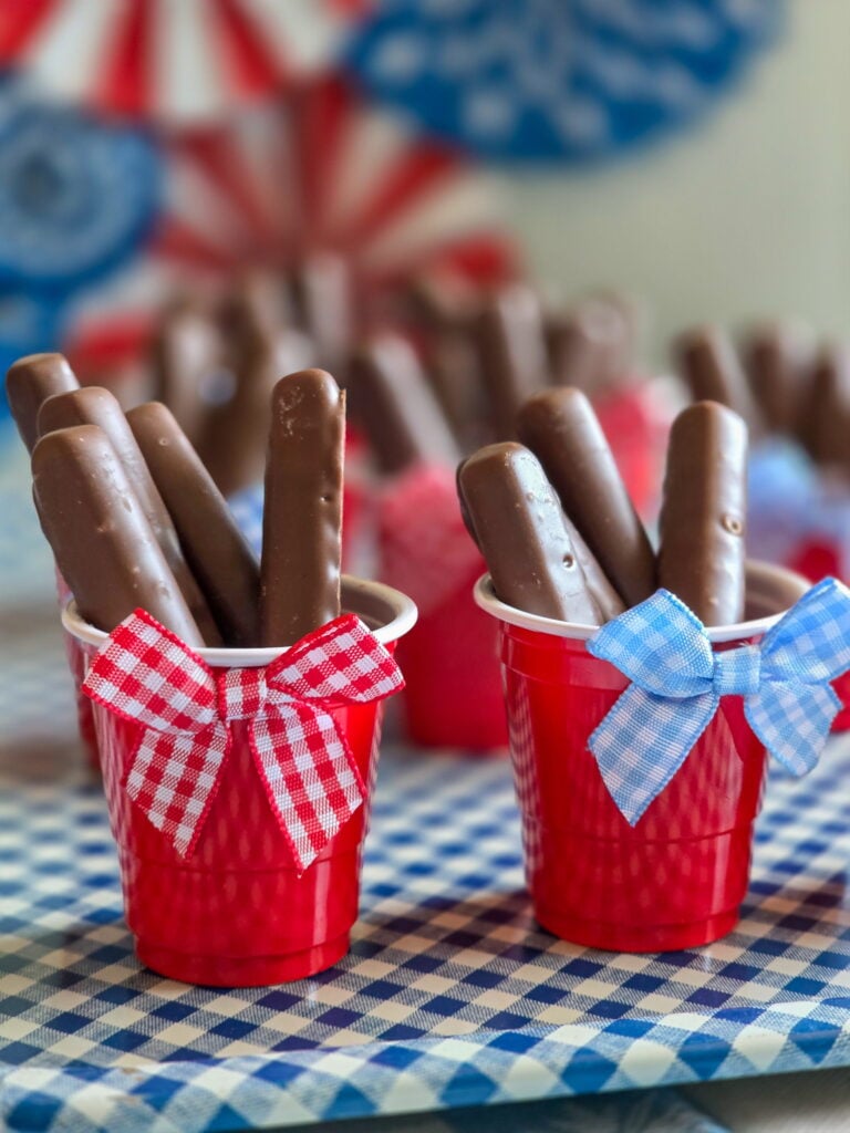 DIY vintage Americana party favor with chocolate raspberry sticks in mini red cups and gingham bow