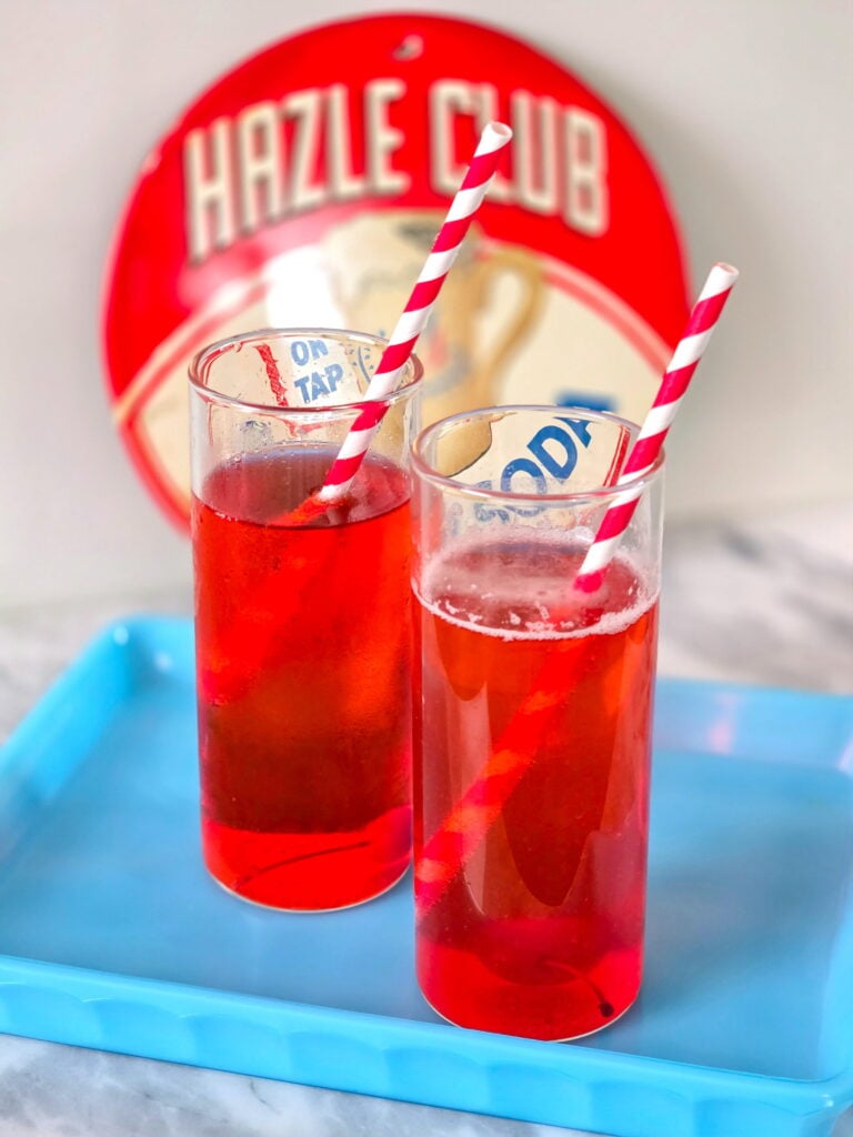 old-fashioned cherry phosphate soda in tall glass with retro straws sitting on a blue tray