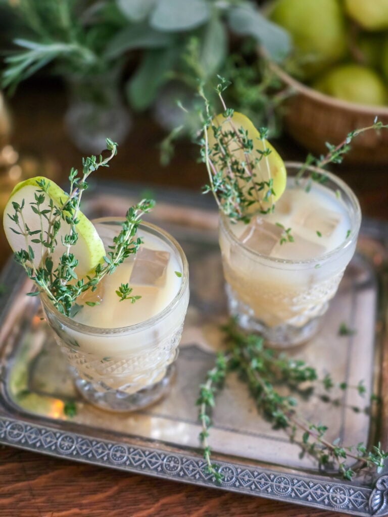 gin pear cocktail in vintage glass with thyme sprig garnish